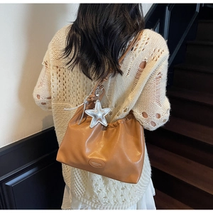 Detail of caramel pleated leather shoulder bag with chic silver star charm accent