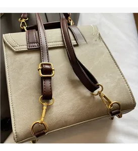 Detail of adjustable brown leather straps and gold metal hardware on a beige backpack