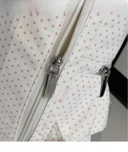 Detailed close-up of smooth silver metal zipper on polka dot print fabric backpack