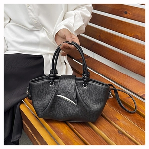 Detail of black lychee grain leather tote with pleated design and silver metal accent