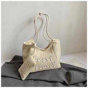 Detail of canvas tote set with yellow stripes, letter patch, and thin shoulder straps