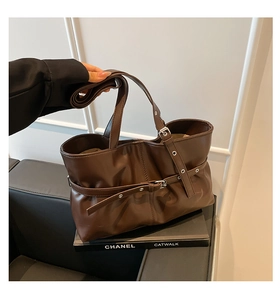 Détail d'un sac cabas en cuir marron foncé avec ceinture décorative et boucle argentée