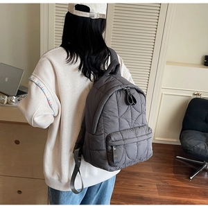 Detail of dark gray quilted backpack with heart stitching on soft nylon fabric