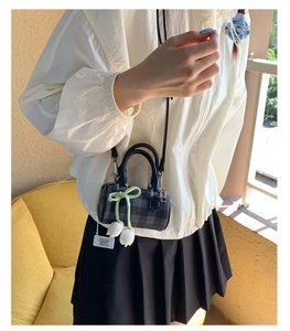 Détails d'un mini sac cylindre à carreaux avec un pendentif fleur de tulipe blanche