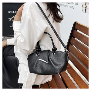 Detail of black lychee grain leather handbag with silver clasp and knotted handle