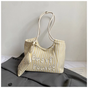 Detail of yellow and white striped canvas tote bag set with branded letter patches