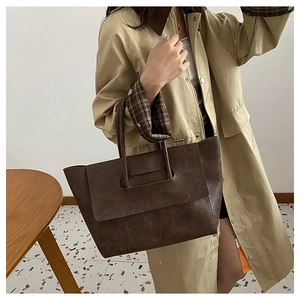 Street style shot of a dark brown large tote bag with natural leather texture