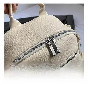 Detailed macro view of the cream leather backpack featuring dual polished metal zippers