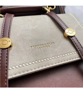 Detail of color-block backpack showing grey fabric, brown leather, and gold lettering