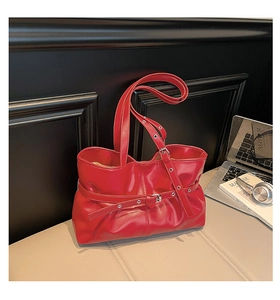Détail d'un sac cabas rouge en similicuir brillant avec boucle métallique et bandoulière