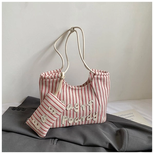 Detail of red striped canvas tote bag with 3D letter patches and faux leather handles