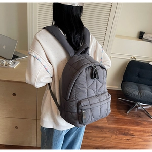 Side view of dark grey quilted backpack with wave pattern stitching for daily travel