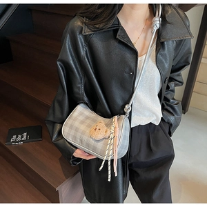 Fashionable grey checkered crescent bag shown in a stylish over-the-shoulder model view