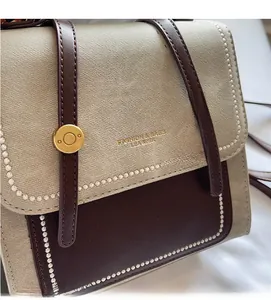 Detail of color-block crossbody bag with gold hardware and embossed fashion logo