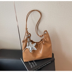 Gros plan sur un cabas en cuir marron avec détails plissés et pendentif étoile argent