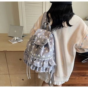 Detail of light purple polka dot backpack featuring ruffled edges and metal buckle straps
