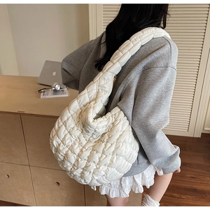 Detail of white quilted nylon cloud bag featuring plush texture and wide hobo shoulder strap