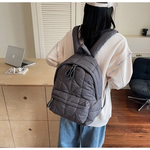 Detail showing the quilted dark grey backpack texture and adjustable shoulder straps