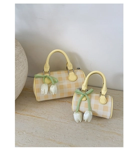 Detail of yellow checkered cylinder bag with floral tulip charms and green ribbons