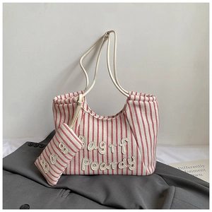 Detail view of red and white striped canvas tote bag with embroidered letters on suit