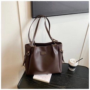 Dettaglio della borsa tote in pelle marrone scuro con coulisse e anello in metallo oro