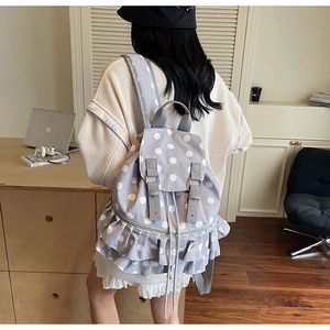 Detail of light purple polka dot backpack featuring ruffle trim and leather buckle straps