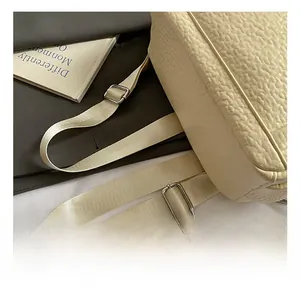 Detailed close-up of adjustable nylon strap with silver metal buckle on a beige backpack