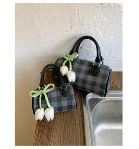 Détails de sacs cylindriques à carreaux avec poignées en cuir et breloques tulipes