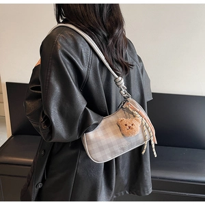 Close-up of checkered hobo bag with wide silver strap and plush bear charm detail