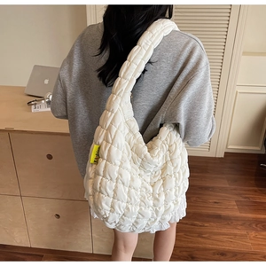 Detail view of the white quilted puffy hobo bag with a distinctive yellow fashion label