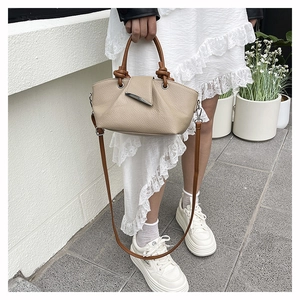 Detailed view of beige lychee texture leather bag with silver buckle and knot handle