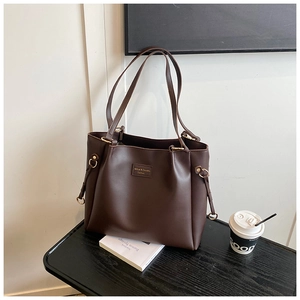 Dettaglio della grande borsa tote in pelle marrone scuro con anello in metallo e logo del brand