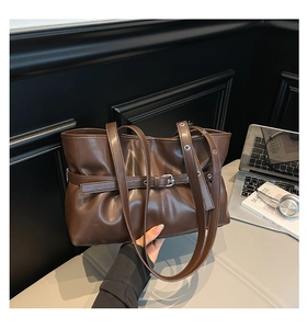 Détail d'un sac cabas marron foncé avec texture plissée et œillets métalliques chic