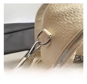 Close-up of beige lychee grain leather bag with silver hooks and jacquard woven strap