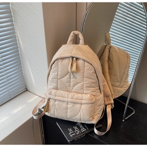 Close-up of beige quilted down fabric backpack with wave stitching and light texture