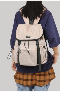 Macro detail of beige hiking backpack featuring drawstring closure and functional pockets