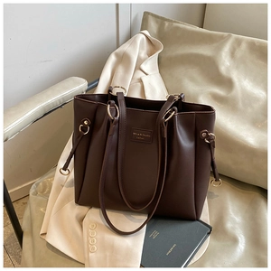 Dettaglio della borsa tote in pelle marrone scuro con anelli dorati e etichetta logo