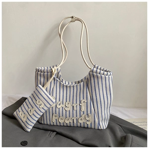 Detail of blue and white striped canvas tote bag with letter patches and a small matching pouch