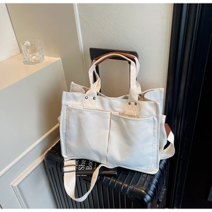 Detail of canvas tote bag with outer pockets and leather handle on a suitcase