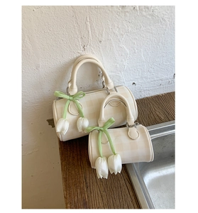 Détail de sacs cylindriques crème à carreaux avec breloques tulipes et nœuds verts