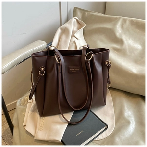Dettaglio della borsa tote in pelle marrone cioccolato con fibbia in metallo ed etichetta