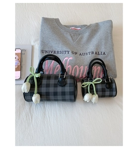 Flat lay of plaid cylinder handbags with white tulip charms and casual lifestyle props