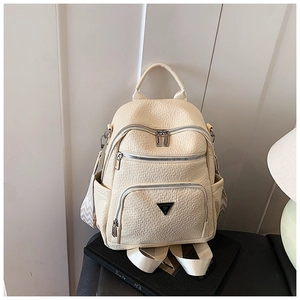 Detail view of cream white pebbled leather backpack with multiple zip pockets and V-pattern strap