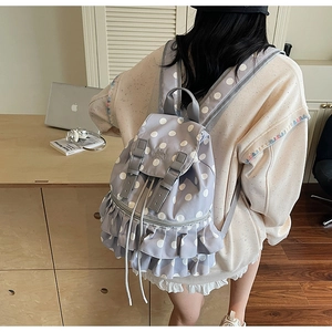 Detail of ruffled lace trim and white polka dot pattern on light blue casual backpack