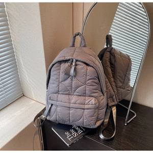 Detail view of the gray quilted nylon backpack texture and front zipper pocket detail