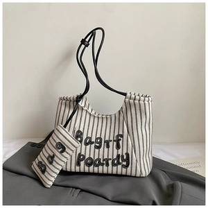 Detail of striped canvas tote bag with hanging pouch and black straps on a blazer