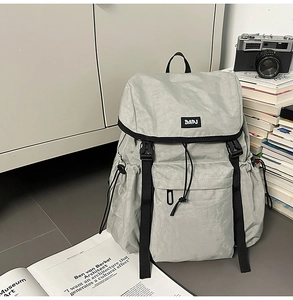 Detail of grey nylon backpack featuring DAPJ brand label and adjustable buckle closure