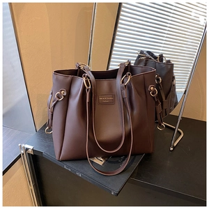 Dettaglio della borsa tote marrone scuro con anelli in metallo dorato e pelle sintetica