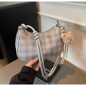 Detail of silver checkered shoulder bag with metallic finish and cute plush bear charm