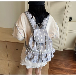 Detail of light purple polka dot backpack featuring elegant ruffle trim and leather straps